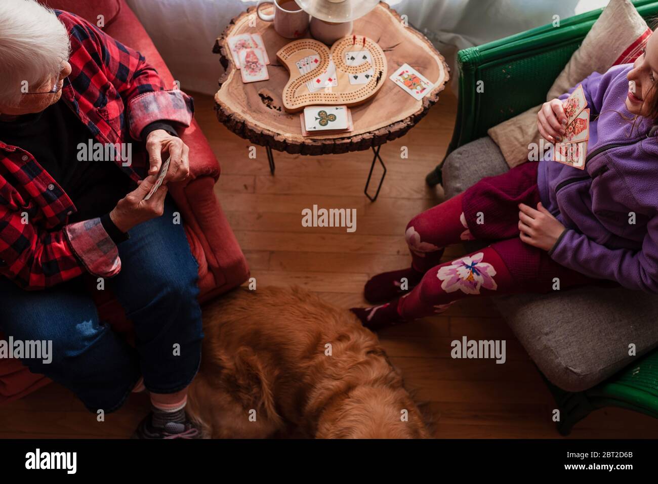 Grandmother and granddaughter playing a card game with dog lying on floor Stock Photo