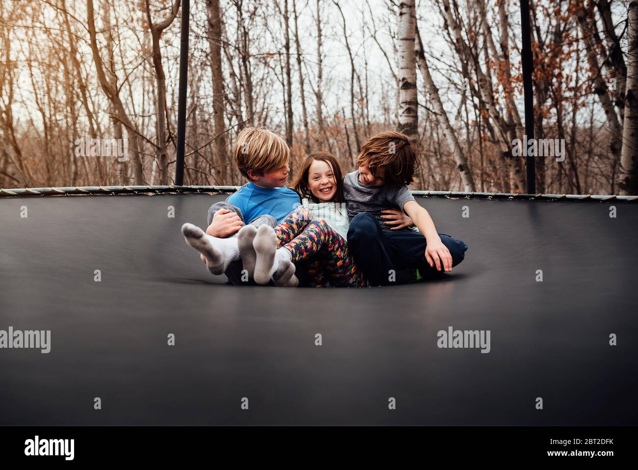 Three children playing on a trampoline, USA Stock Photo