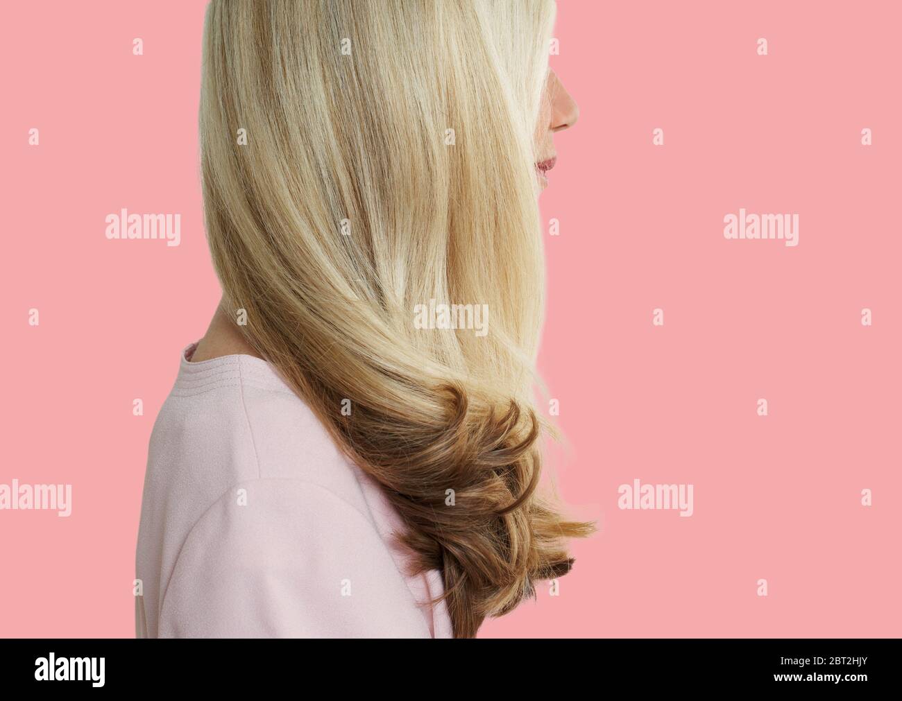 Senior woman with long blonde hair standing over pink background Stock Photo