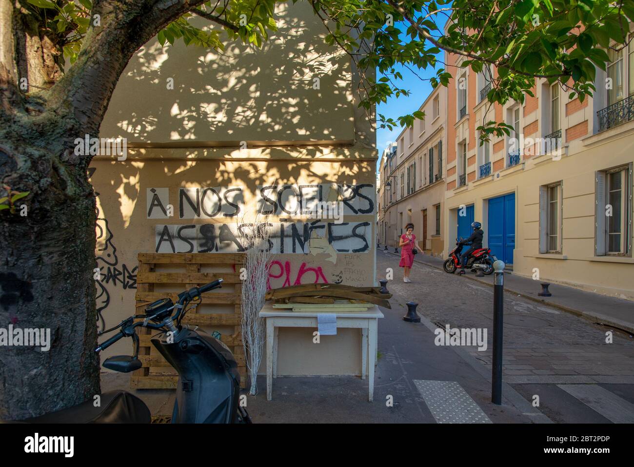 Paris, France - May 17, 2020: Graffiti saying 'to our murdered sisters', with a woman passing by, taken at the end of the day, Butte-aux-Cailles Stock Photo