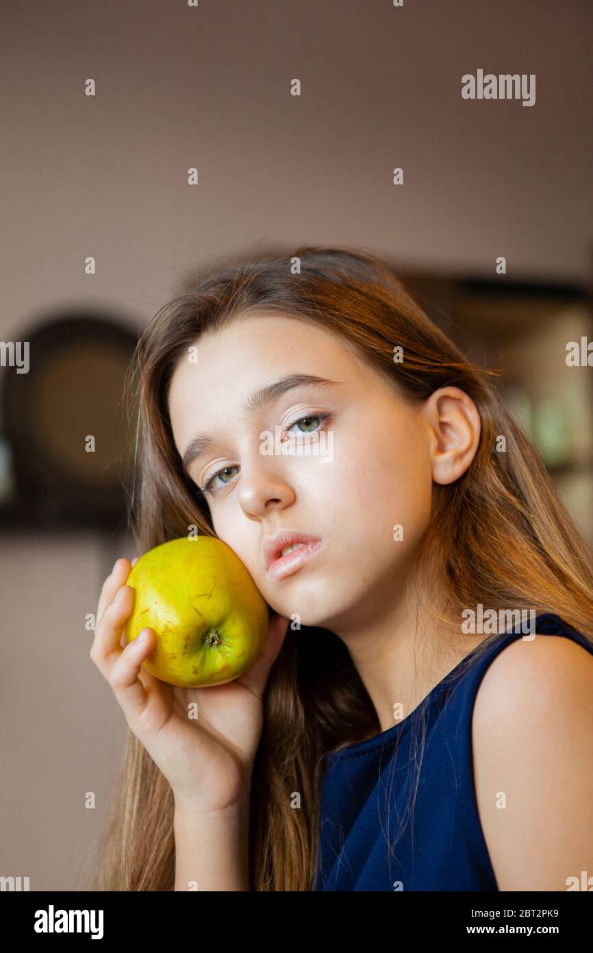 young pensive girl holding a green sour apple Stock Photo