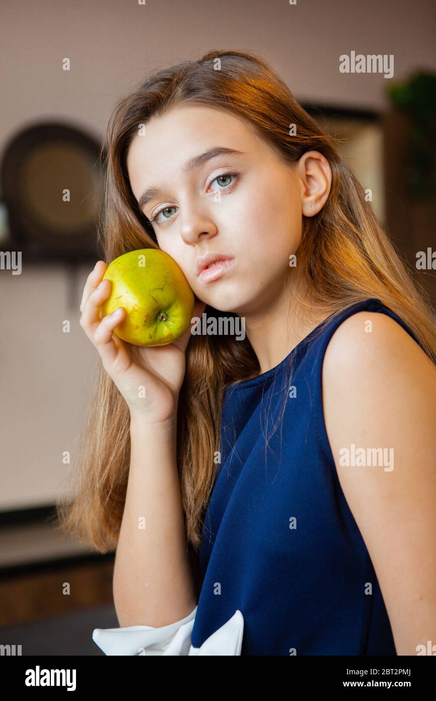 pensive girl holding a green sour apple Stock Photo