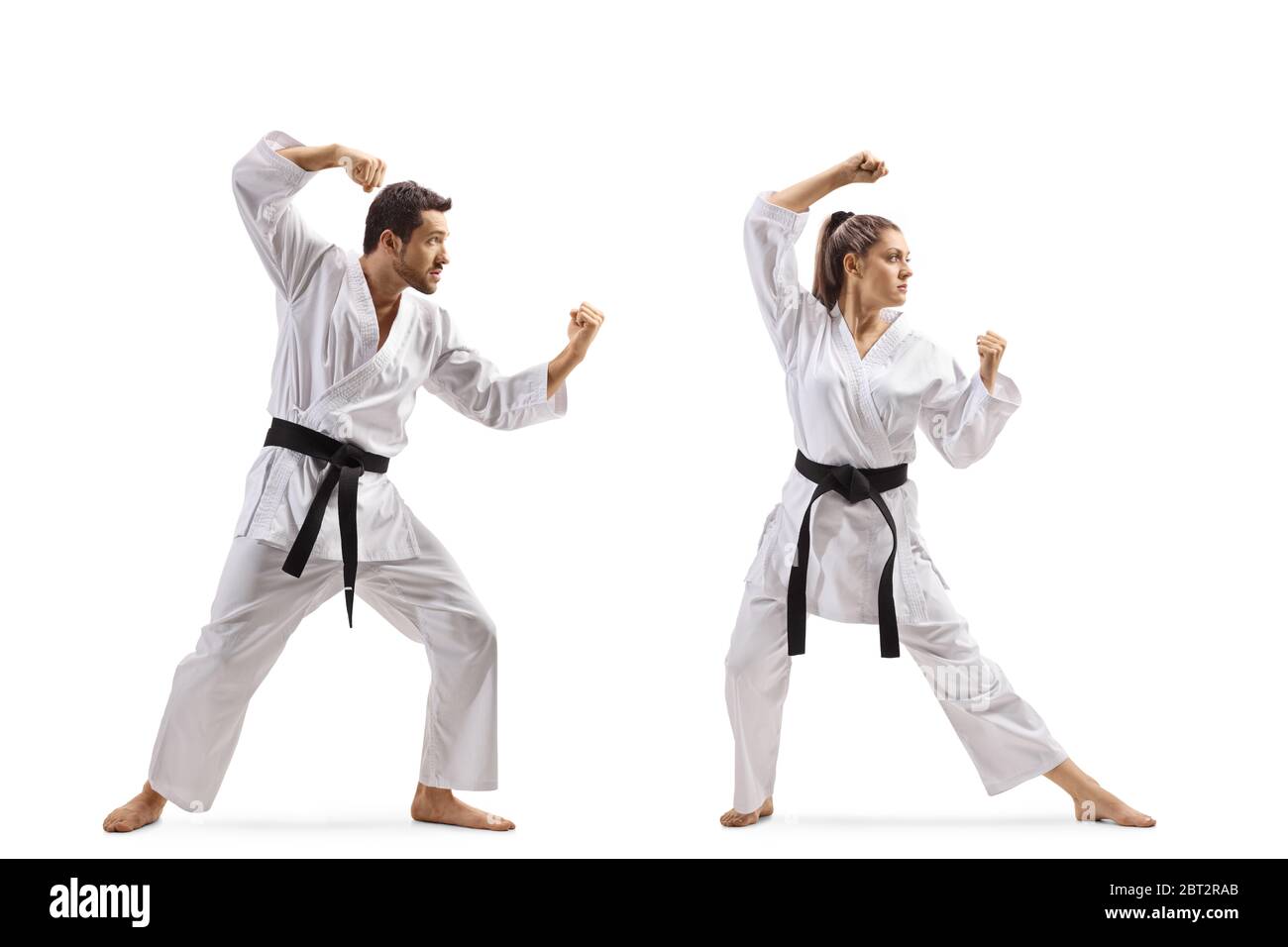 Full length shot of a young man and woman with black belts practicing karate isolated on white background Stock Photo