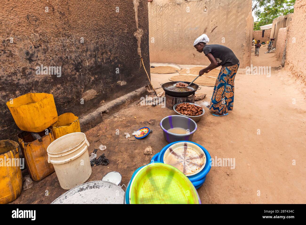 African girl in colorful clothes and turban making traditional sweet cookies outdoor kitchen local manufacture Stock Photo