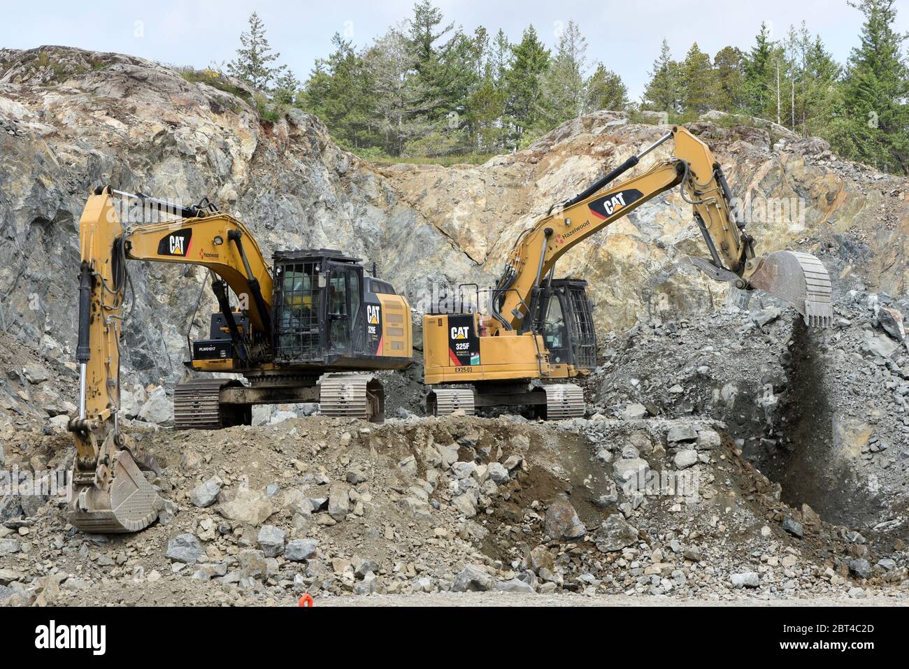 Two CAT (Caterpillar) brand excavators work at moving broken rock at a development site off of MCCallum Road in the greater Victoria municipality of L Stock Photo