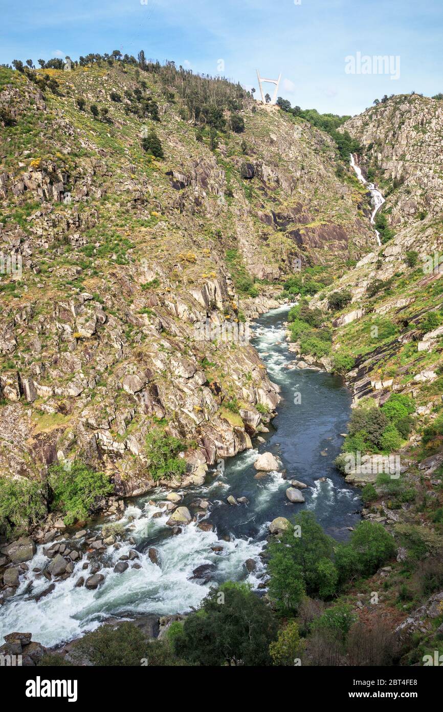 Landscape of the Paiva gorge with the Paiva river and its rapids in the foreground and the Aguieiras waterfall in the background. Stock Photo