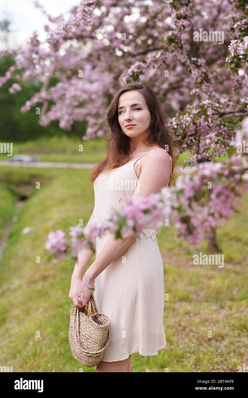 A young beautiful girl stands by a blooming Apple tree Stock Photo - Alamy