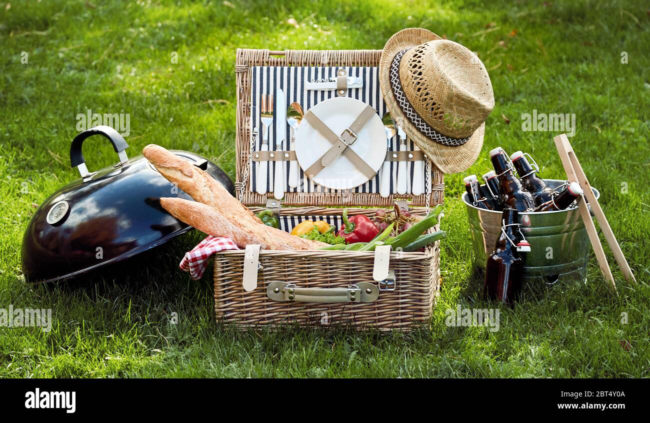 Panorama banner with vegetarian or vegan picnic hamper filled with fresh salad ingredients, grapes and crusty baguettes alongside a silver cooler fill Stock Photo
