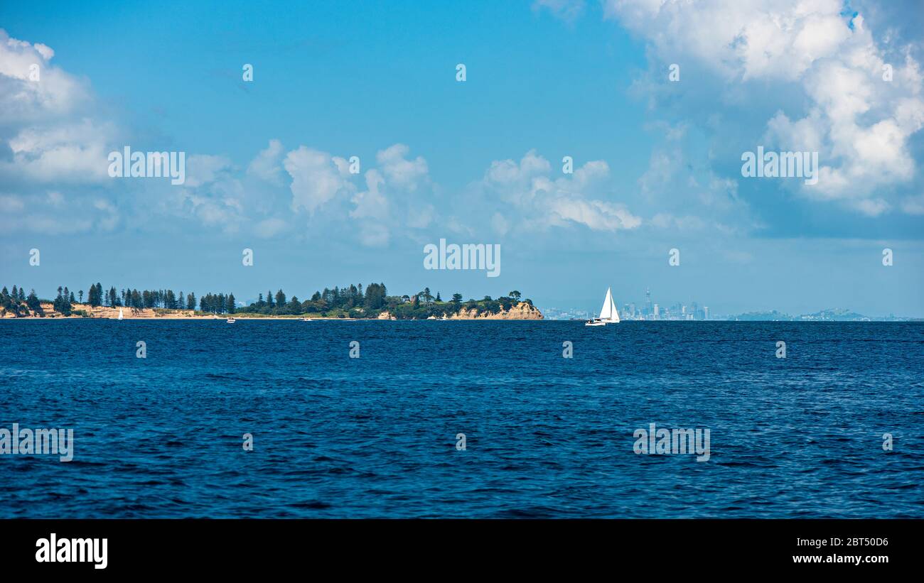 A sailboat on a tranquil blue sea on a cloudy day in Auckland Stock Photo