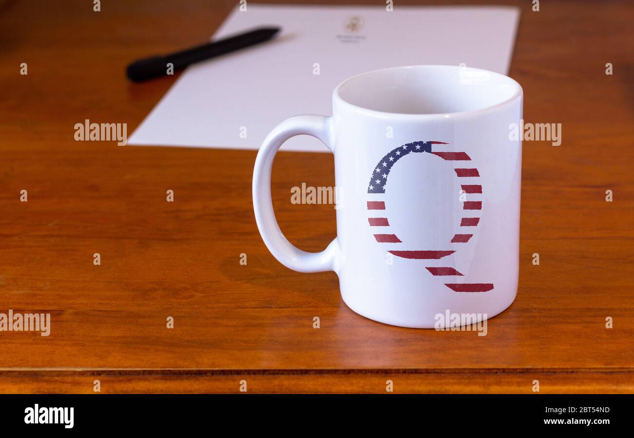 QAnon symbol on white mug on wooden desk, conspiracy theory, deep state conservative concept Stock Photo