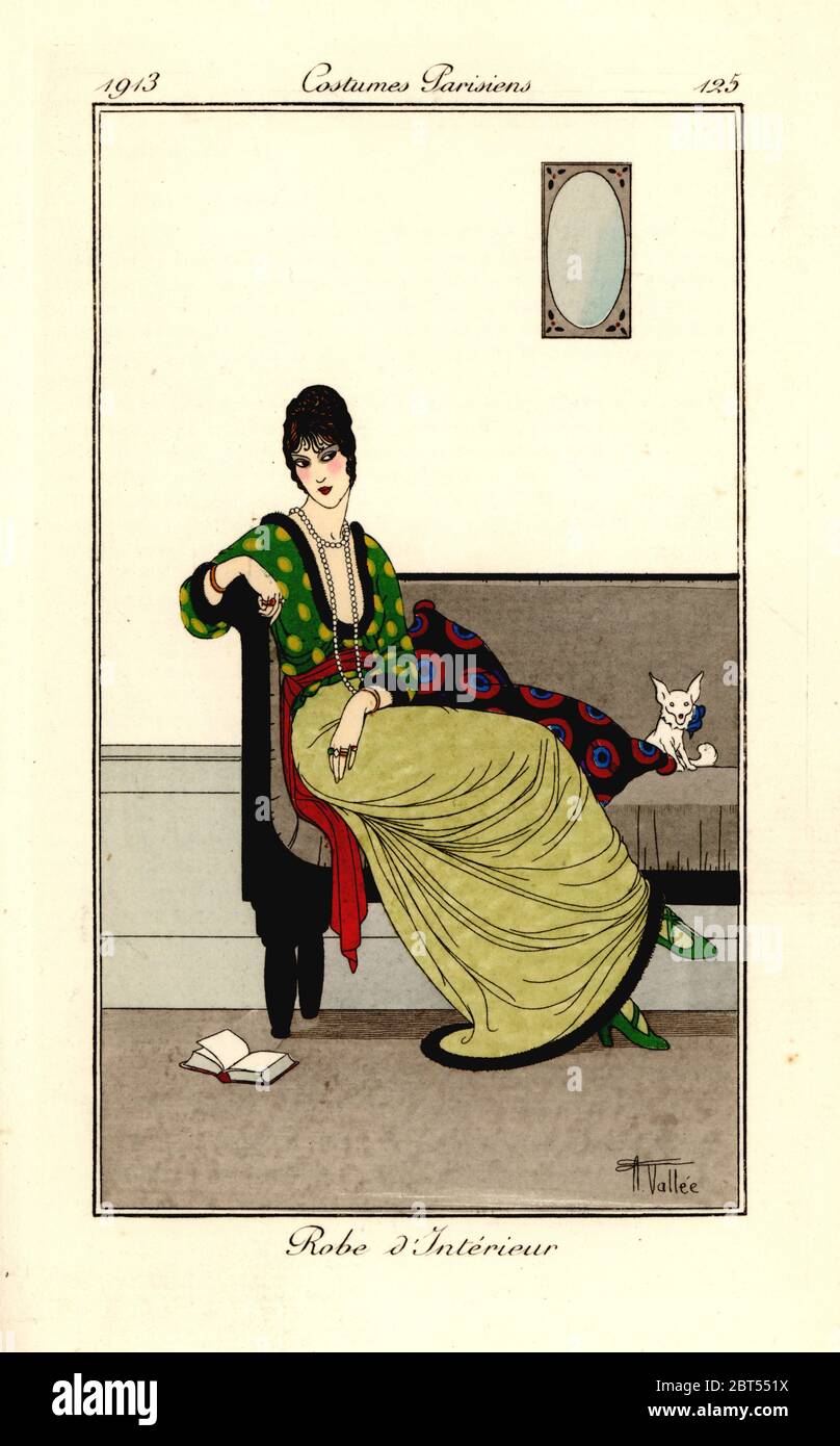 Woman in fashionable outfit seated on a sofa with pet dog, 1913. Robe dinterieur. Handcoloured pochoir (stencil) etching after an illustration by Armand Vallee from Tommaso Antonginis Journal des Dames et des Modes, Aux Bureaux du Journal des Dames, Paris, 1913. Stock Photo