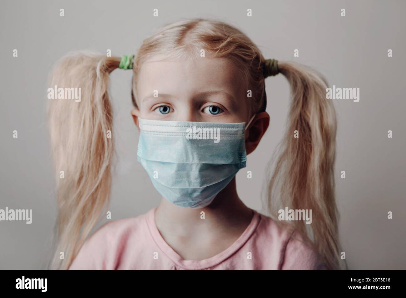 Portrait of Caucasian blonde girl in sanitary face mask. Preschool child wearing protective mask against coronavirus. Concept of safety and health pro Stock Photo