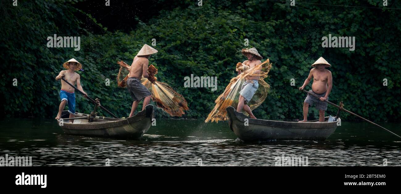 HUE - MAR 07, 2018: Four Vietnamese fishermen sailing boats while catching fish with fishnets on Song Nhu Y River in Hue, Vietnam on 07 March 2018 Stock Photo