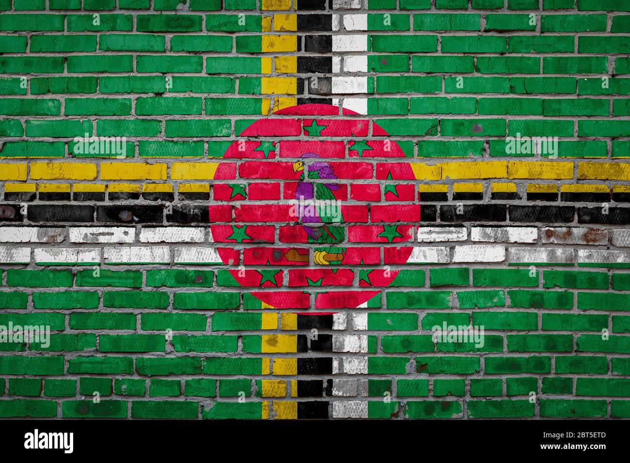 National flag of Dominica depicting in paint colors on an old brick ...