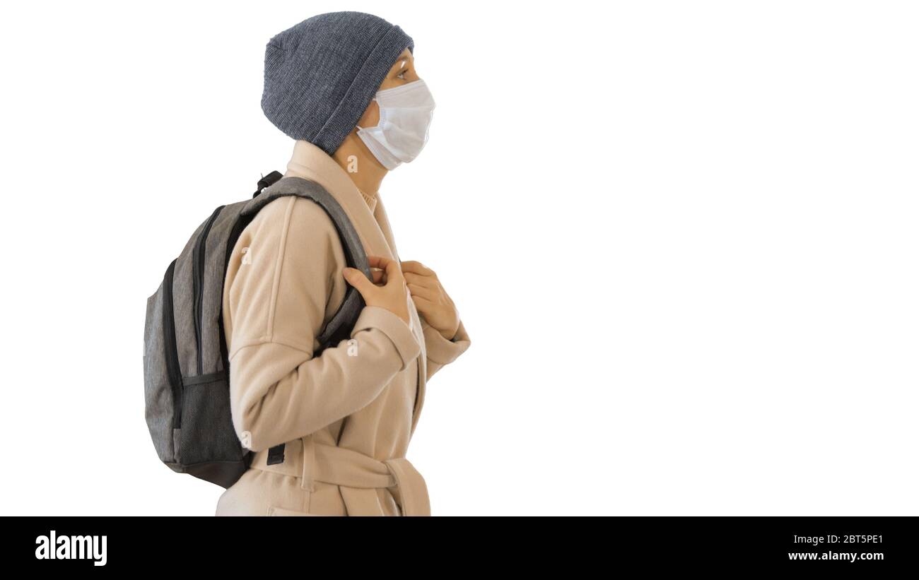 Covid-19 virus prevention, woman wearing a medical mask on her face walking on white background. Stock Photo