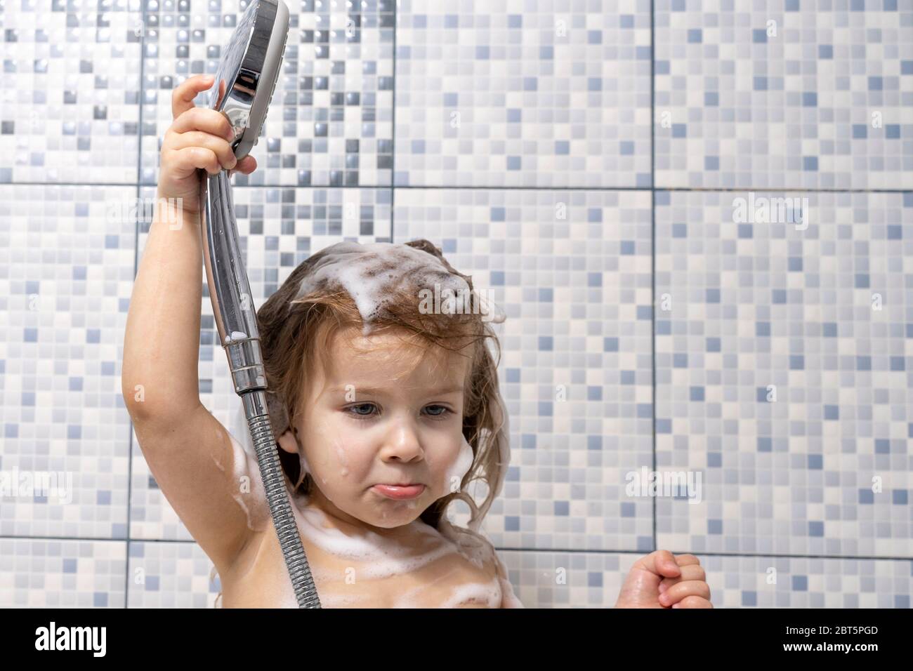 a little girl in foam is standing in the bathtub in her hand holding a