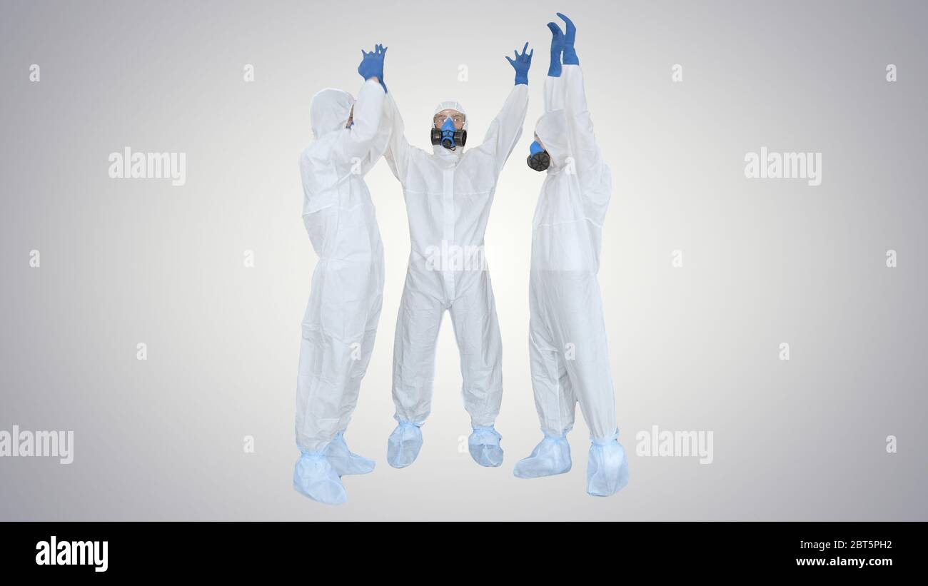 Doctors in hazamat suits stacking hands Team work on gradient background. Stock Photo
