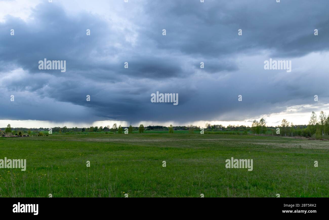 landscape with dark stormy skies on a contrasting green field ...