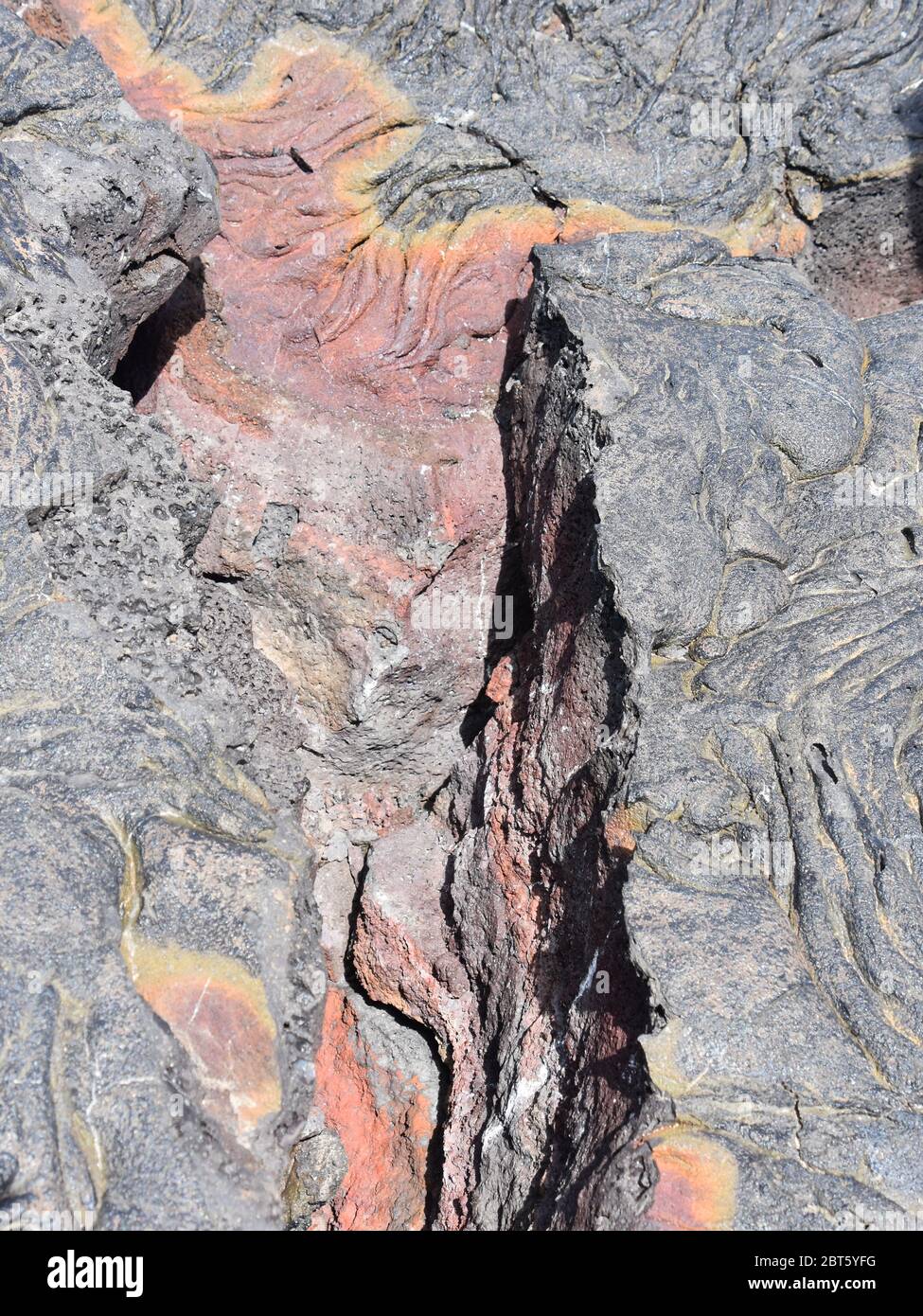 Crack in igneous rock dry lava colorful minerals Stock Photo