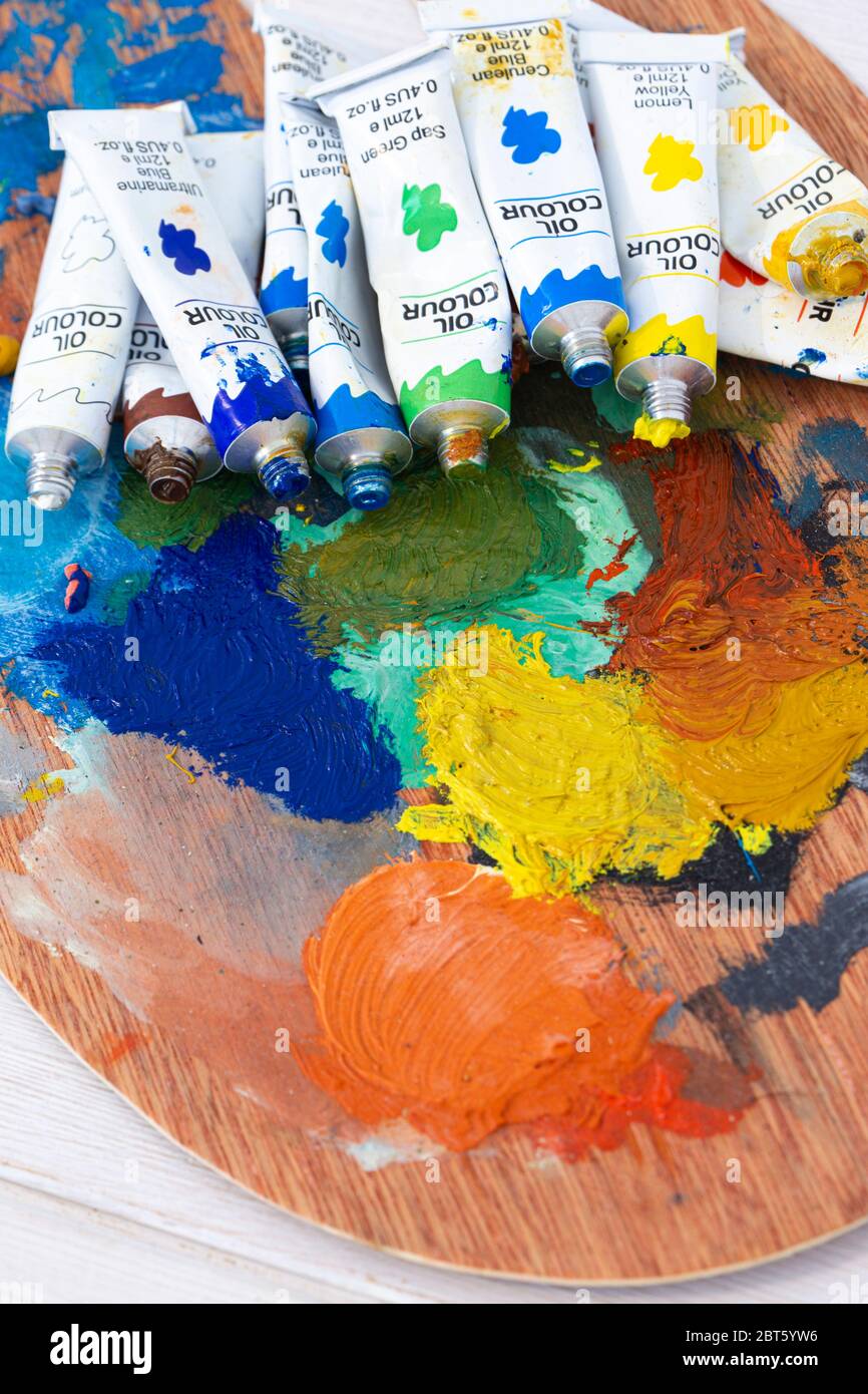 Artists oil paint tubes open and used on a wooden palette, with mixed