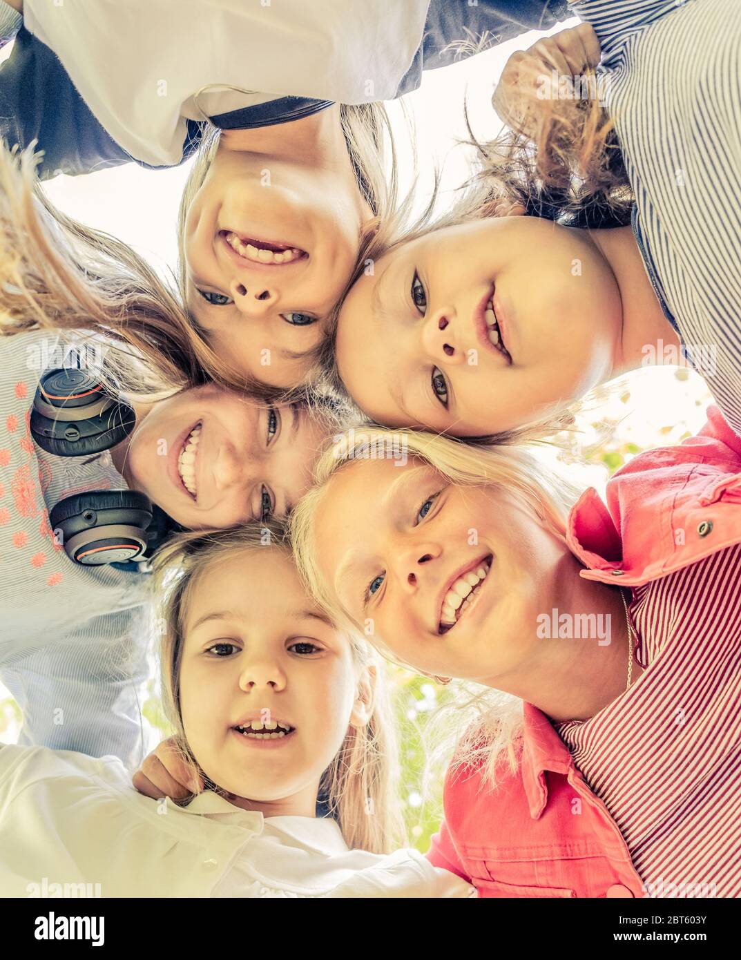 Shot from below of happy smiling little girls standing in circle Stock Photo