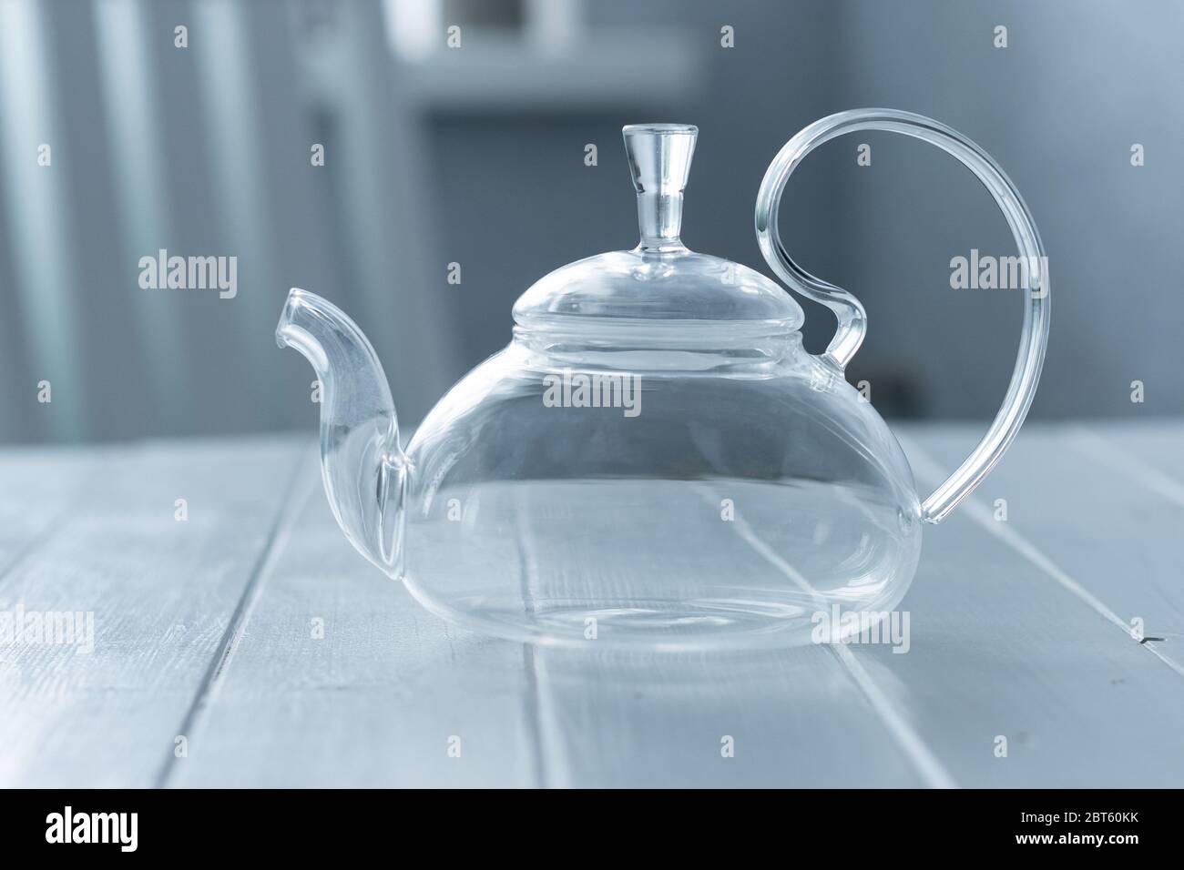 Empty transparent teapot on wooden kitchen table Stock Photo