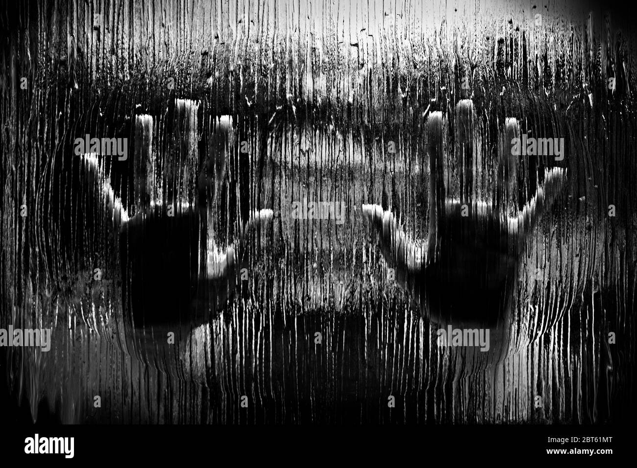 Black and white image of hands pressed against a frosted glass window