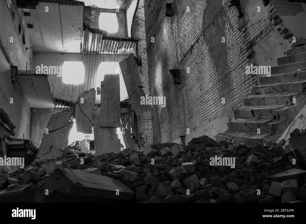 Black and white image. Destroyed concrete building inside with a pile of construction debris in