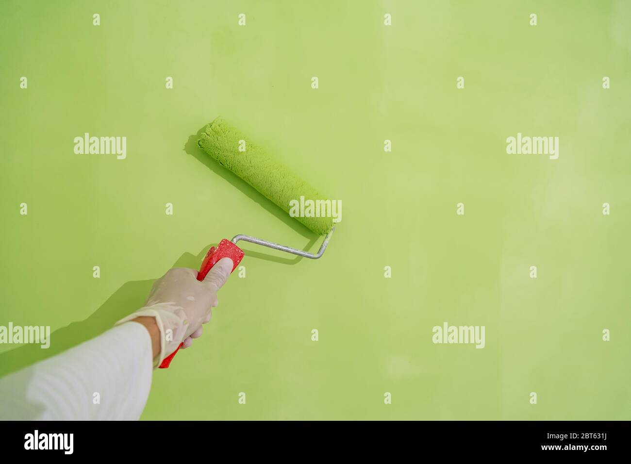 Painter with painting brush in hand painting a wall green Stock Photo