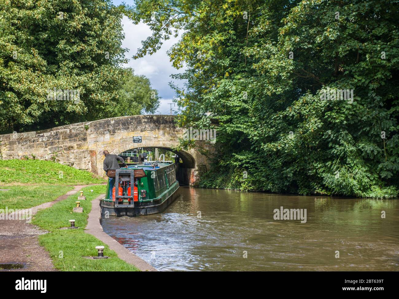A narrowboat negotiating its way beneath a canal bridge on the Staffordshire and Worcestershire canal on a sunny summer august day in England. Stock Photo