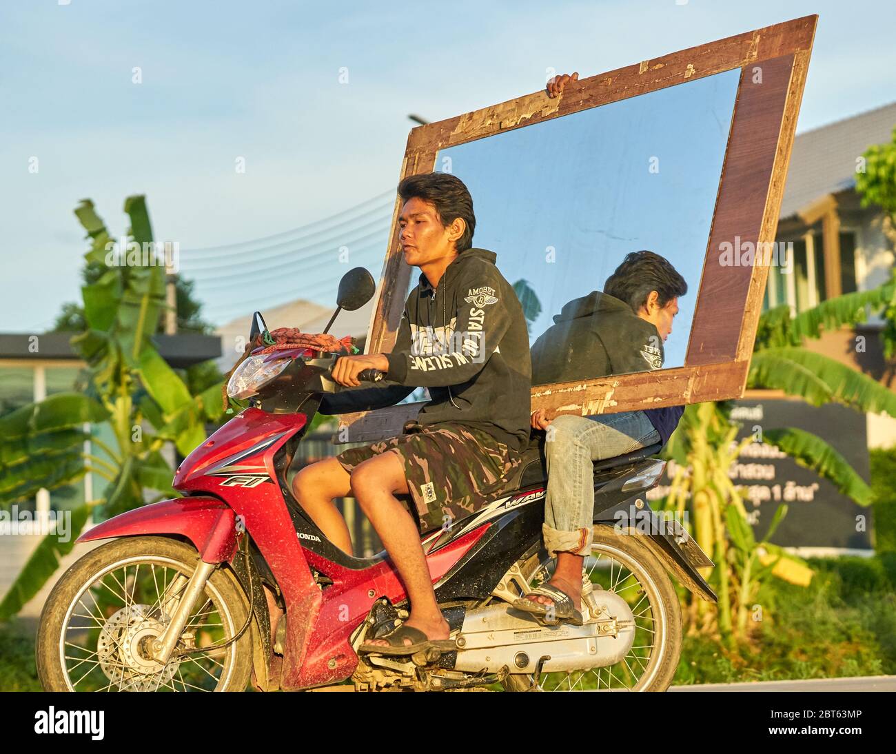 Two men on a scooter carrying a large mirror. Stock Photo