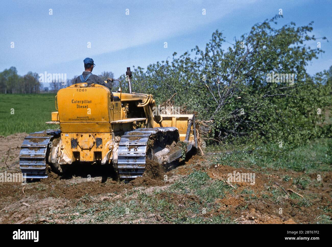 A farmer clearing his land on a Caterpillar D6 track-type diesel tractor on a family farm, USA in the early 1950s. Stock Photo