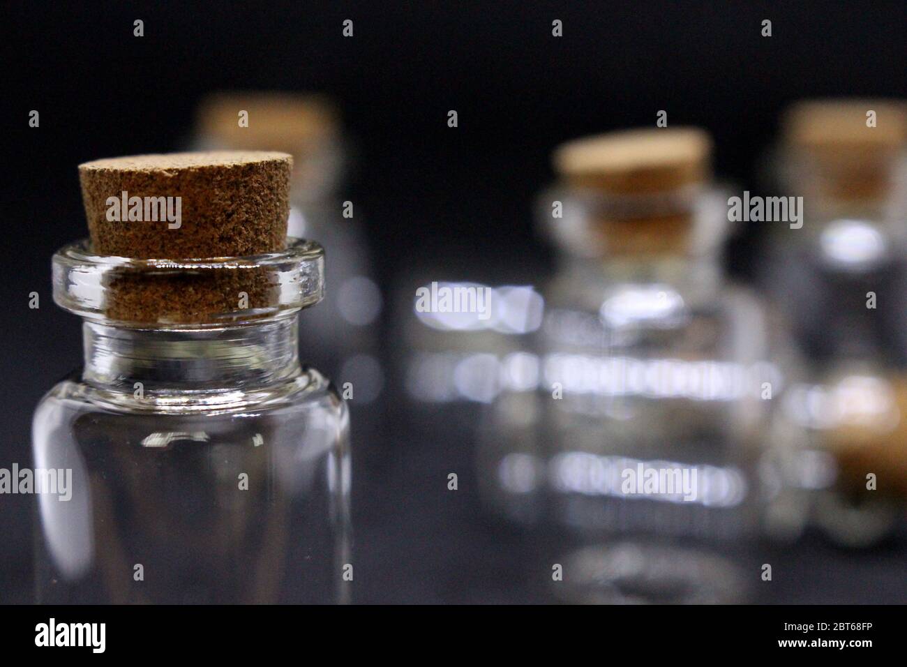 A close up photograph of empty glass bottles with cork stoppers, against a black background Stock Photo