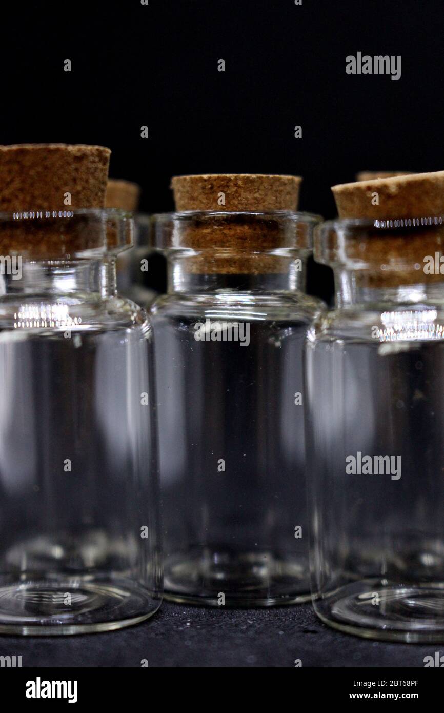 A close up photograph of empty glass bottles with cork stoppers, against a black background Stock Photo