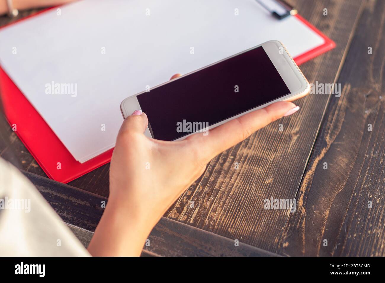 Download Mockup Image Of A Hand Holding White Mobile Phone With Blank Black Desktop Screen On Background Of White Sheet Of Paper At A Cafe Stock Photo Alamy PSD Mockup Templates