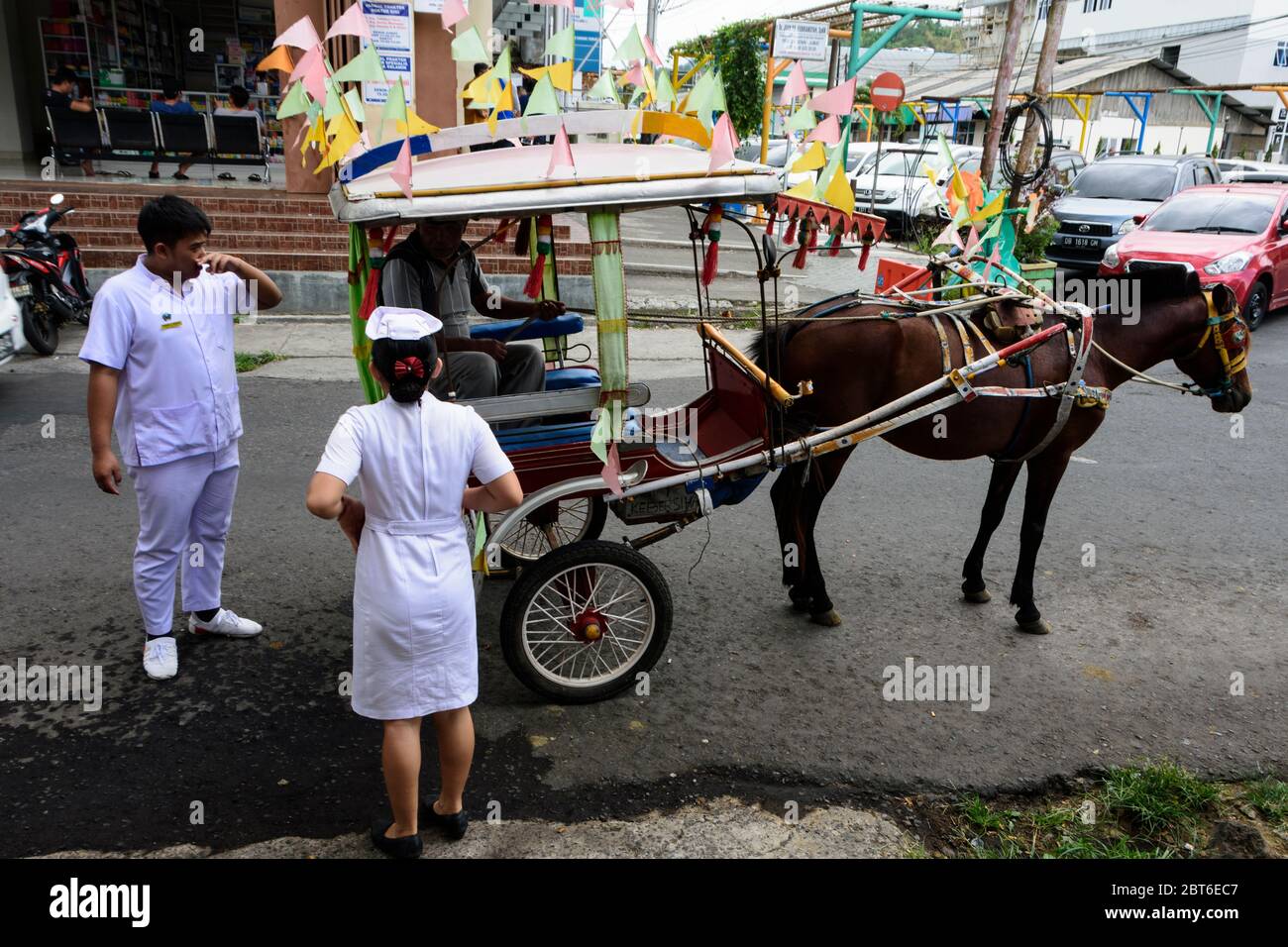 Two (para) medics ready to climb a 'Bendi' , the traditional local transport, Tomohon, Sulawesi, Indonesia. Stock Photo