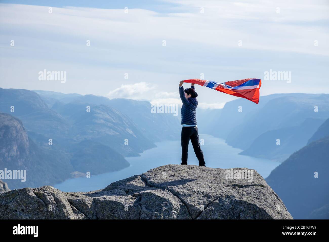 Woman with a waving flag of Norway on the background of nature Stock Photo