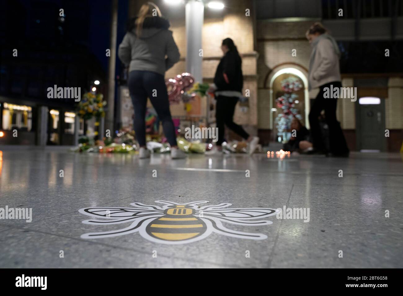 Manchester, UK. 22nd May, 2020. A Manchester bee symbol placed on the ground to encourage social distancing is seen as members of the public stand by a memorial to the victims of the Manchester Arena Bomb at Manchester Victoria Railway Station as the 3rd Anniversary of the terror attack is marked with a minuteÕs silence, Manchester, UK. Credit: Jon Super/Alamy Live News. Stock Photo