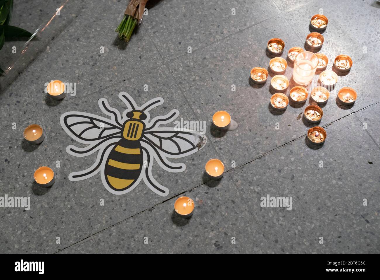 Manchester, UK. 22nd May, 2020. A Manchester bee symbol placed on the ground to encourage social distancing is seen surrounded by candles by a memorial to the victims of the Manchester Arena Bomb at Manchester Victoria Railway Station as the 3rd Anniversary of the terror attack is marked with a minuteÕs silence, Manchester, UK. Credit: Jon Super/Alamy Live News. Stock Photo