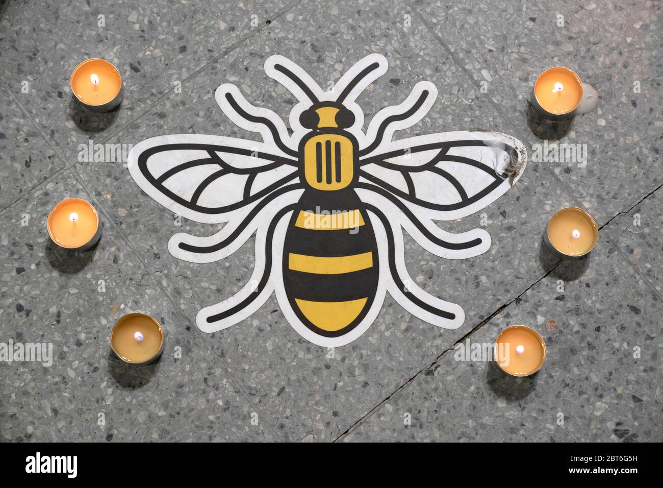 Manchester, UK. 22nd May, 2020. A Manchester bee symbol placed on the ground to encourage social distancing is seen surrounded by candles by a memorial to the victims of the Manchester Arena Bomb at Manchester Victoria Railway Station as the 3rd Anniversary of the terror attack is marked with a minuteÕs silence, Manchester, UK. Credit: Jon Super/Alamy Live News. Stock Photo