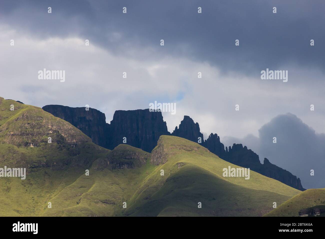 The mountains of the Drakensberg, in South Africa, in the early morning with the prominent shape of the Dragon’s back, in the shadow of a coming storm Stock Photo