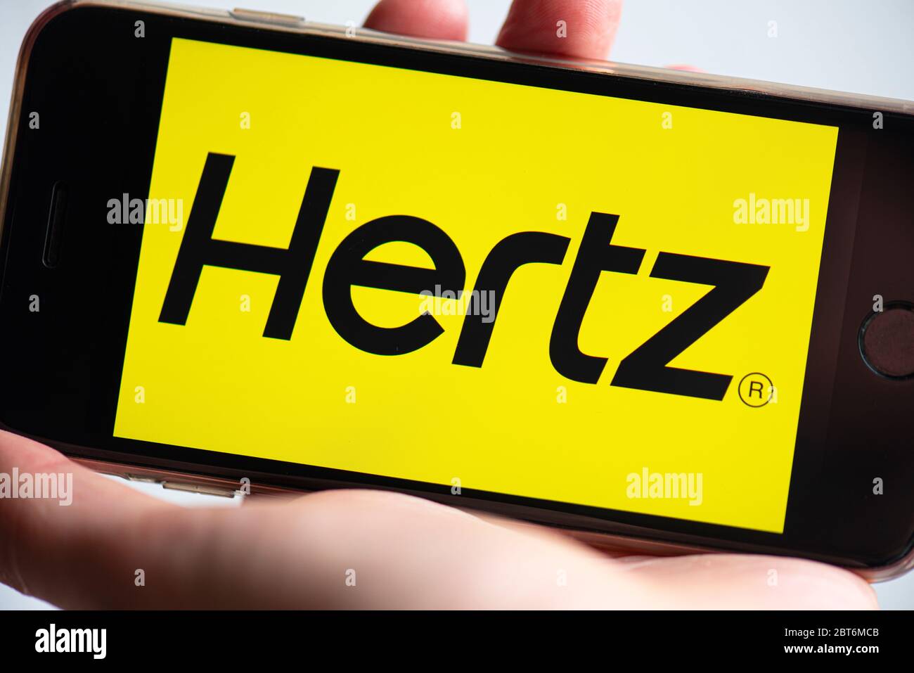 BERLIN - MAY 23: HERTZ App on screen of mobile phone. Man holding phone with Hertz application for rent car in Berlin on 23. 2020 in Germany. Stock Photo