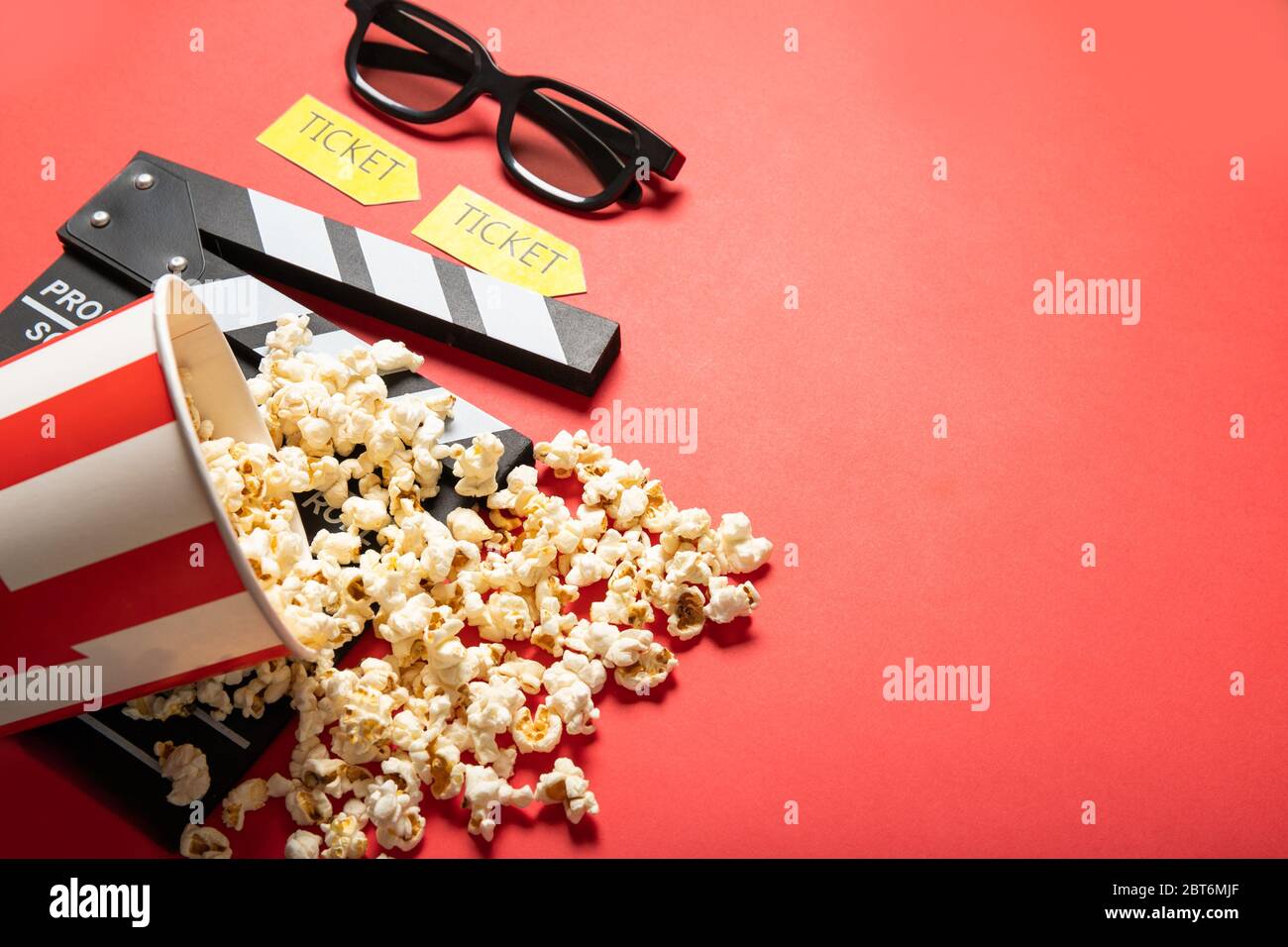 Paper cup with popcorn and movie clapper board on a red background ...
