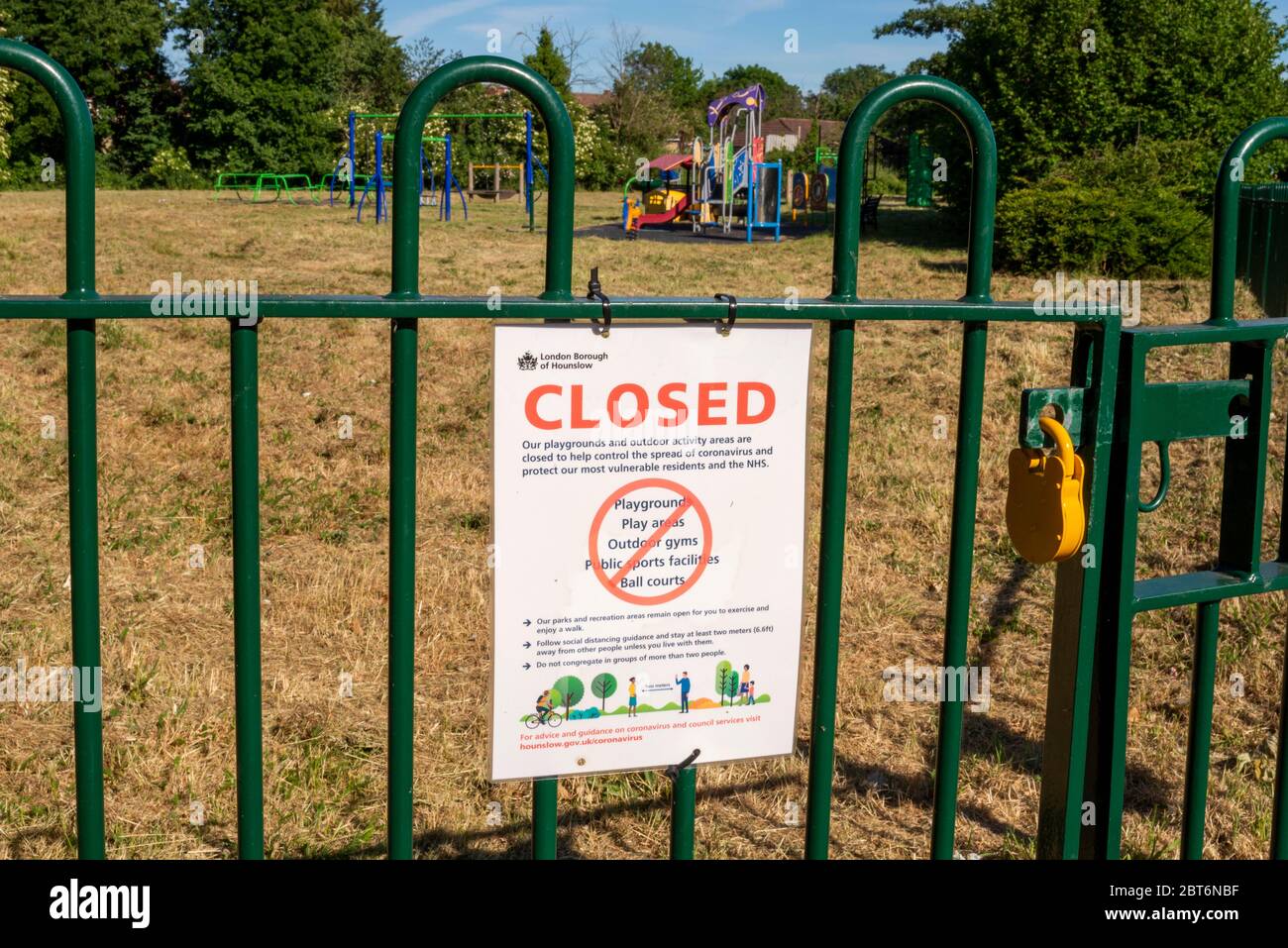 Closed park playground in Cranford, London, UK during COVID-19 Coronavirus lockdown. Shut and locked outside play area with warning sign on sunny day Stock Photo