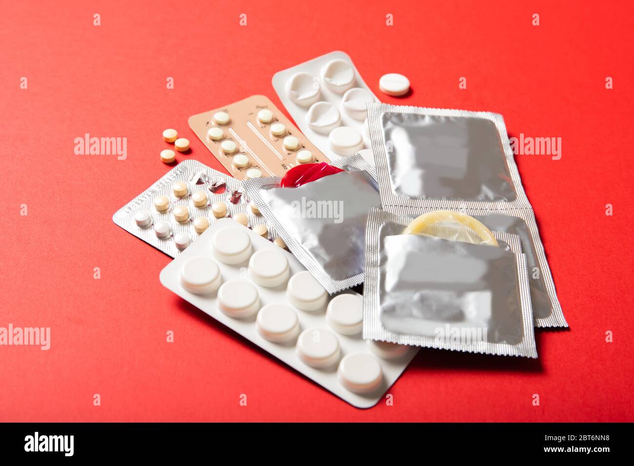 Birth control pills and condoms on a red background. Close-up Stock Photo