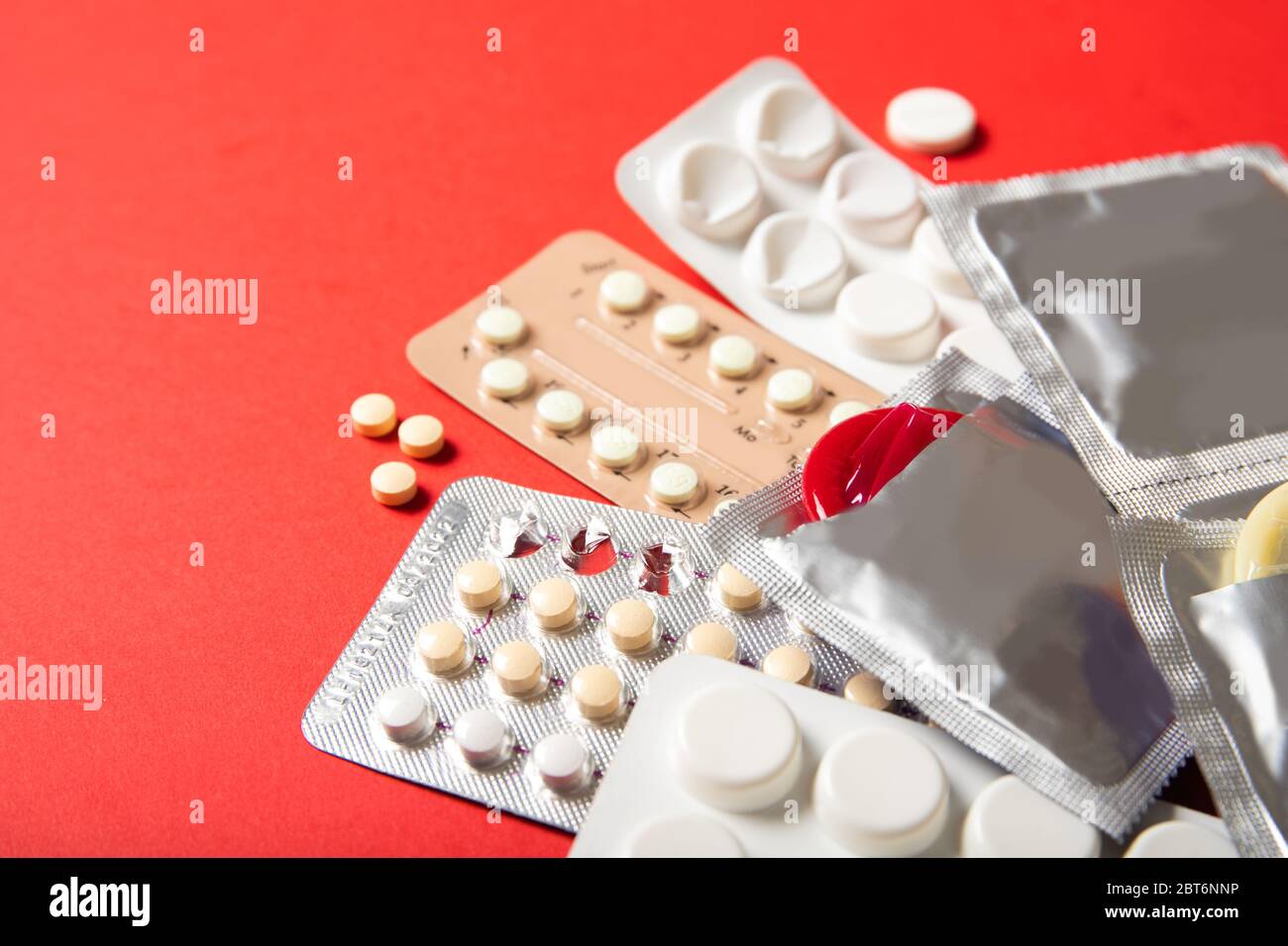 Birth control pills and condoms on a red background. Close-up Stock Photo