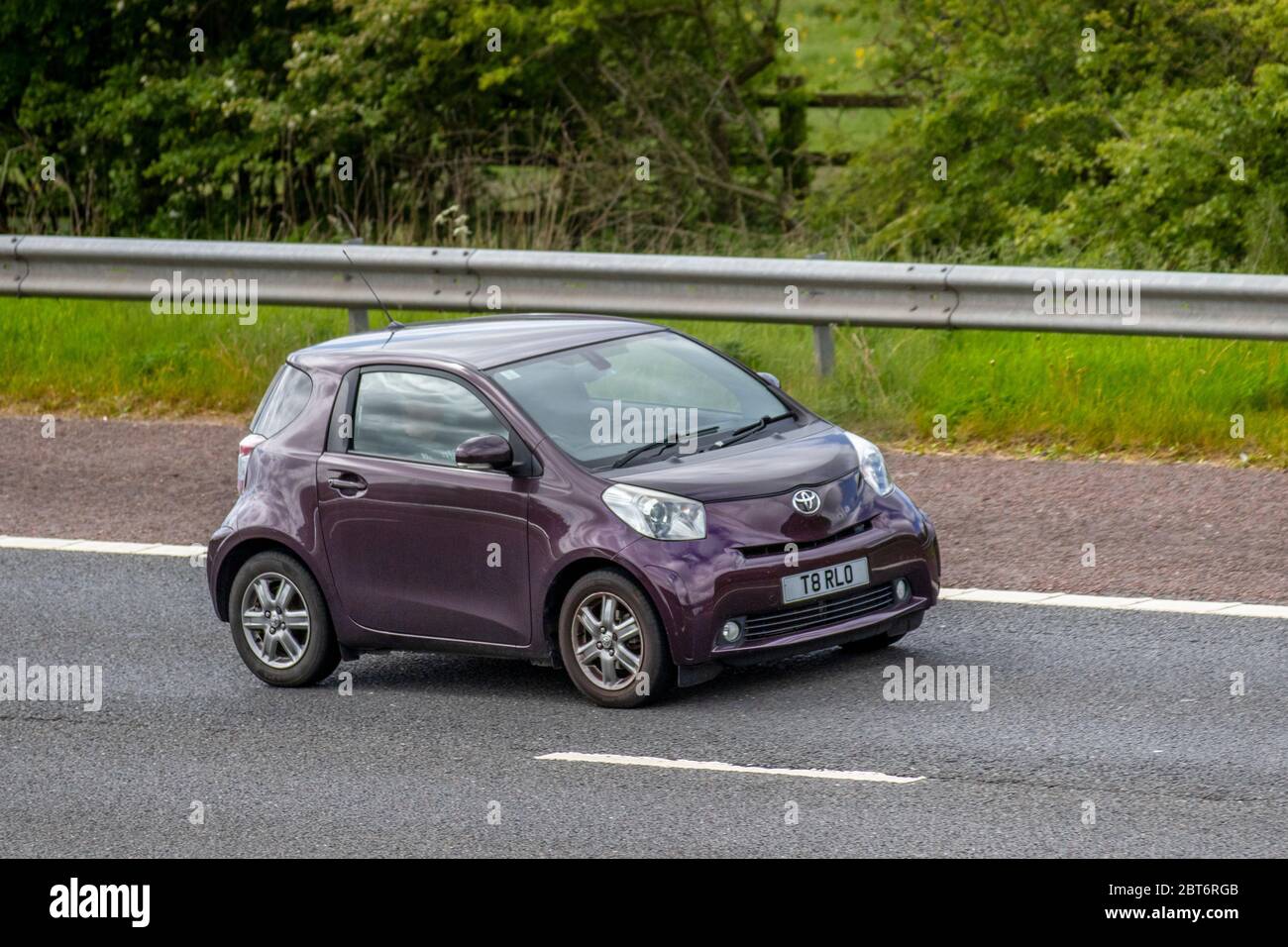 2010 mauve purple Toyota IQ2 VVT-I; Vehicular traffic moving vehicles, cars driving vehicle on UK roads, motors, motoring on the M61 motorway highway Stock Photo
