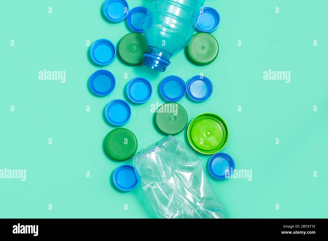 Composition of plastic bottles and plastic bottle caps on green background with space for text. Plastic free concept Stock Photo