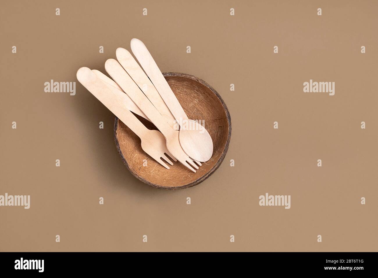 Biodegradable cutlery (spoon, forks, coconut bowl) on neutral brown background. Top view with copy space Stock Photo