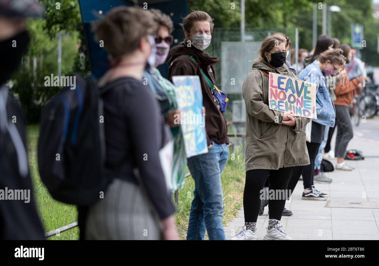 Hanover, Germany. 23rd May, 2020. With a sign '#Leavenoonebehind', demonstrators with face masks during the rally 'Keeping up the pressure' stand for a humane refugee policy. Among other things, they called for an evacuation of the overcrowded camps in Greece, where a humanitarian catastrophe is threatening because of the Corona pandemic. The 'Seebrücke' alliance, which advocates civil sea rescue, safe escape routes and the permanent reception of refugees in Germany, had called for this. Credit: Peter Steffen/dpa/Alamy Live News Stock Photo